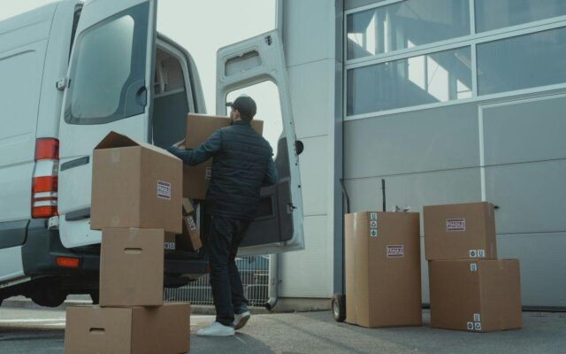 Man unloading moving boxes from a van outside a facility, showing how short term self storage helps during a home move