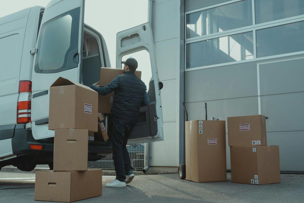 Man unloading moving boxes from a van outside a facility, showing how short term self storage helps during a home move