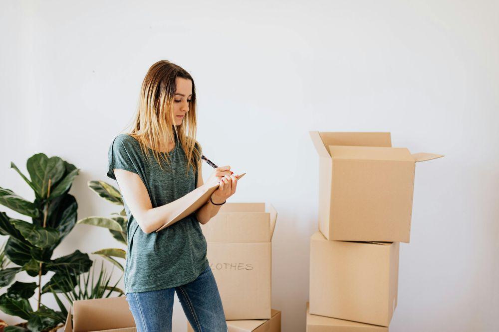 Woman labelling moving boxes in a home setting prep for life events